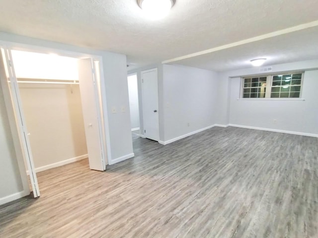basement featuring a textured ceiling and hardwood / wood-style flooring