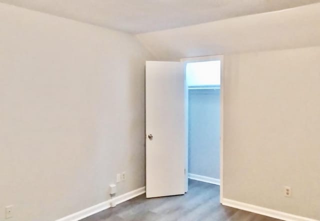 spare room featuring vaulted ceiling and hardwood / wood-style flooring