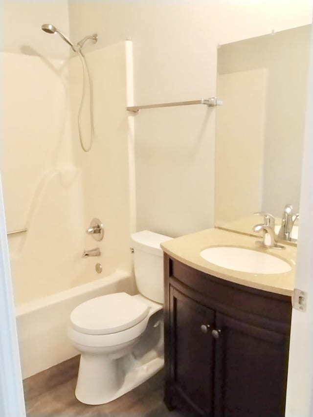 full bathroom with hardwood / wood-style floors, toilet, shower / bathtub combination, and vanity