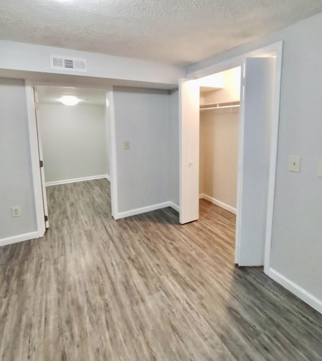 basement featuring wood-type flooring and a textured ceiling