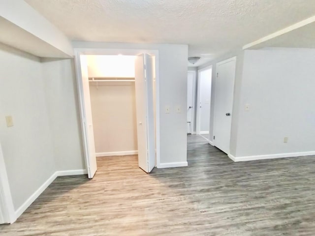 interior space featuring wood-type flooring, a textured ceiling, a closet, and a walk in closet