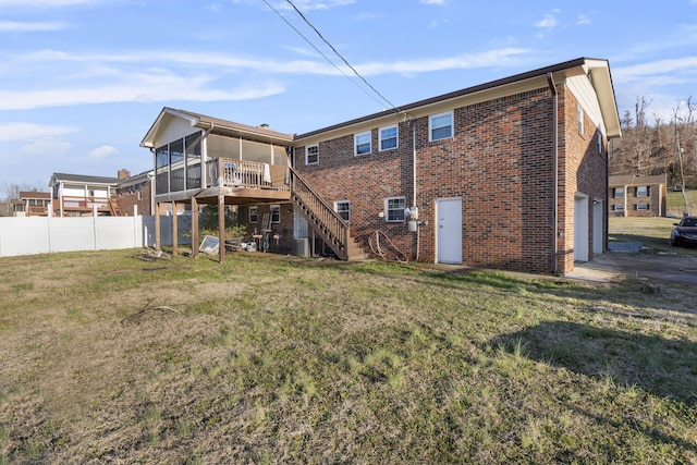 rear view of property with a garage, a lawn, a deck, and a sunroom