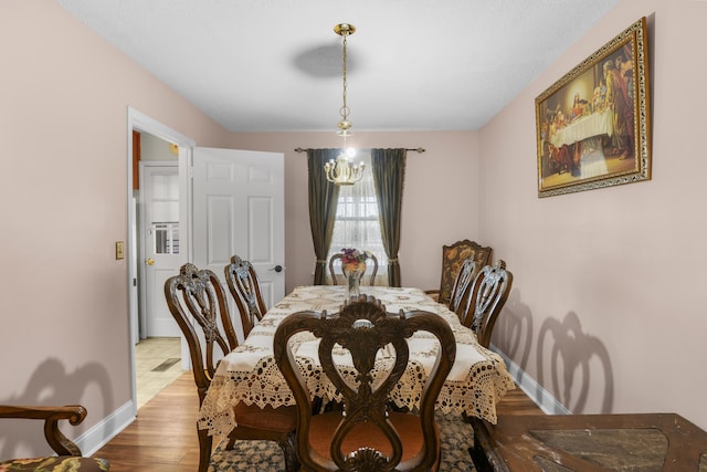 dining room with light wood-type flooring and a chandelier