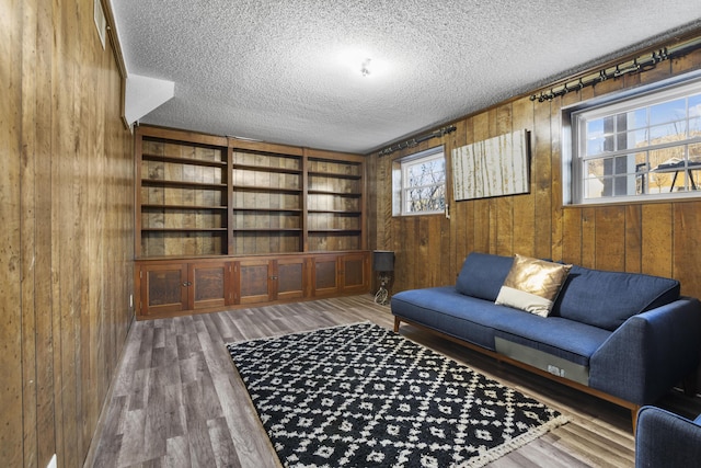 living room featuring hardwood / wood-style floors, a textured ceiling, and wooden walls