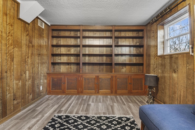 unfurnished room featuring wood walls, a textured ceiling, and built in features