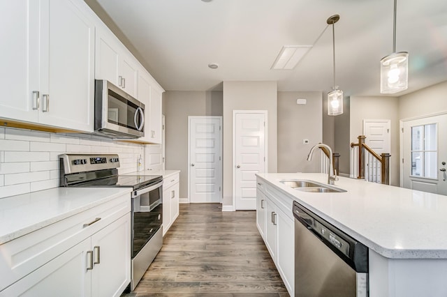 kitchen with appliances with stainless steel finishes, an island with sink, decorative light fixtures, sink, and white cabinetry