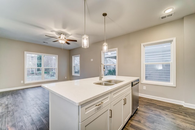 kitchen with an island with sink, white cabinets, stainless steel dishwasher, decorative light fixtures, and sink