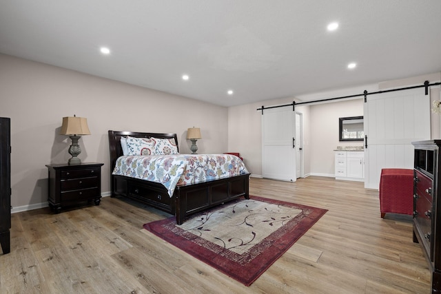 bedroom featuring light wood-style floors, a barn door, baseboards, and recessed lighting