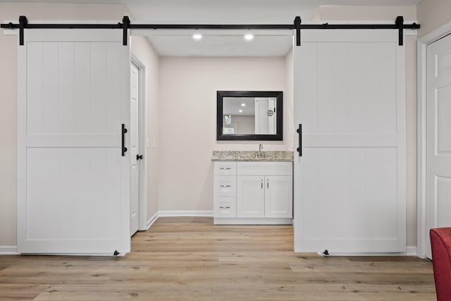 interior space featuring light wood-style floors, a barn door, and baseboards