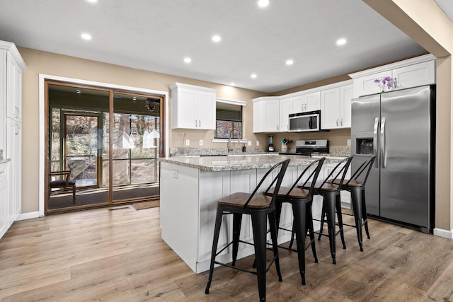 kitchen featuring light wood-style flooring, recessed lighting, white cabinets, appliances with stainless steel finishes, and a center island