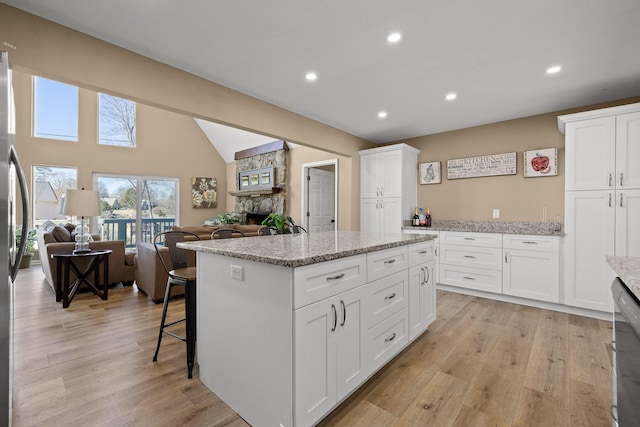 kitchen with open floor plan, a fireplace, a kitchen island, and light wood-style floors