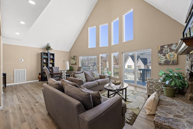 living area featuring light wood-type flooring, high vaulted ceiling, baseboards, and visible vents