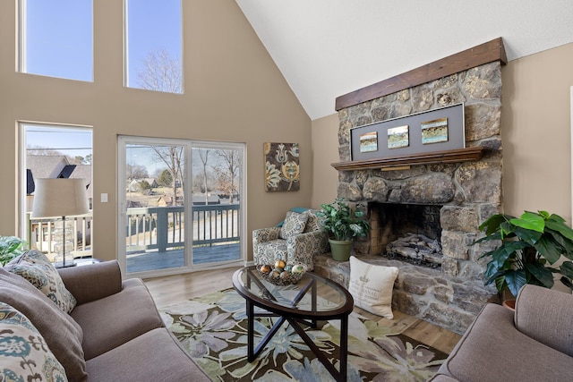 living area with high vaulted ceiling, a fireplace, and wood finished floors