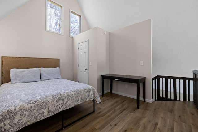 bedroom with high vaulted ceiling, wood finished floors, and baseboards