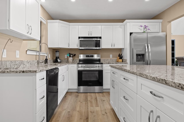 kitchen with appliances with stainless steel finishes, white cabinets, and a sink