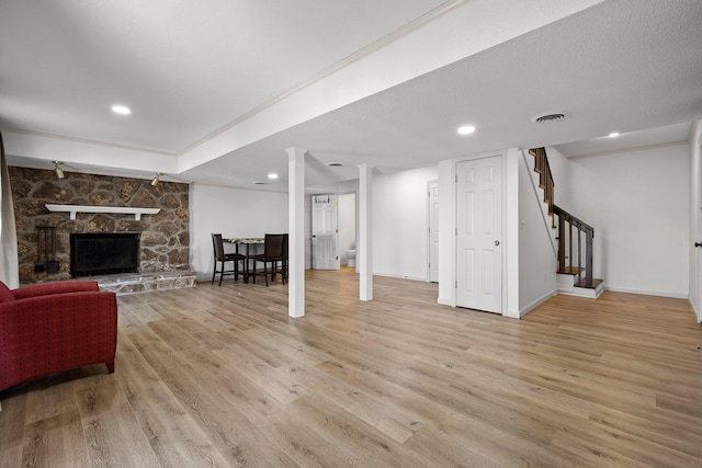 living area featuring light wood finished floors, visible vents, stairway, a stone fireplace, and recessed lighting