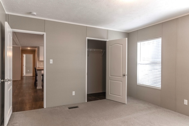 unfurnished bedroom featuring carpet floors, a closet, visible vents, and a textured ceiling