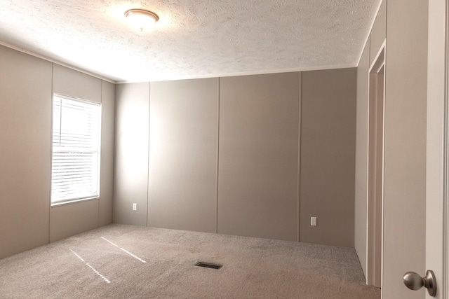 carpeted empty room featuring visible vents and a textured ceiling