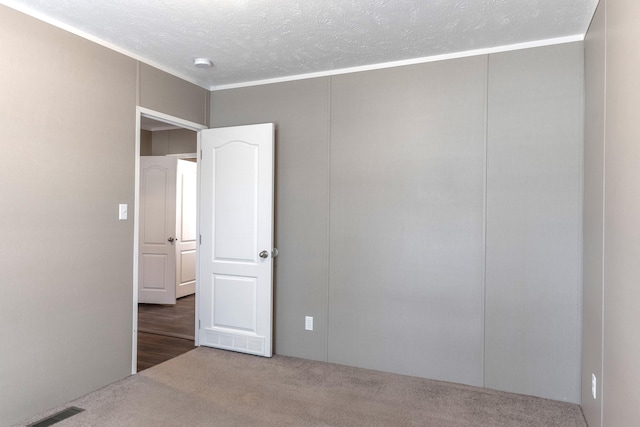 carpeted spare room featuring visible vents and a textured ceiling