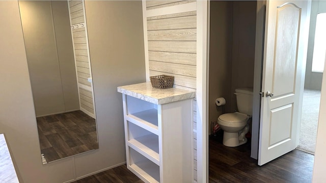 bathroom featuring wood finished floors, toilet, and wooden walls