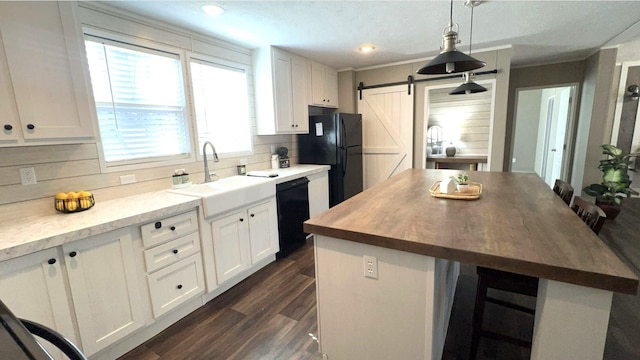 kitchen featuring a barn door, butcher block counters, a kitchen island, white cabinets, and black appliances