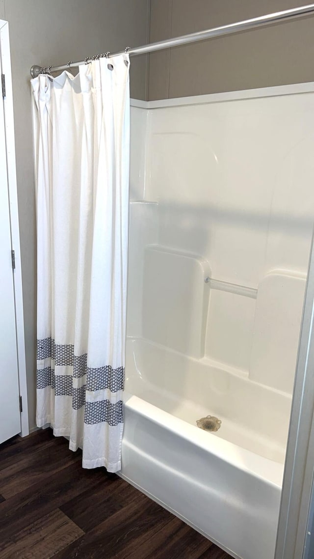 bathroom featuring wood finished floors and shower / tub combo with curtain