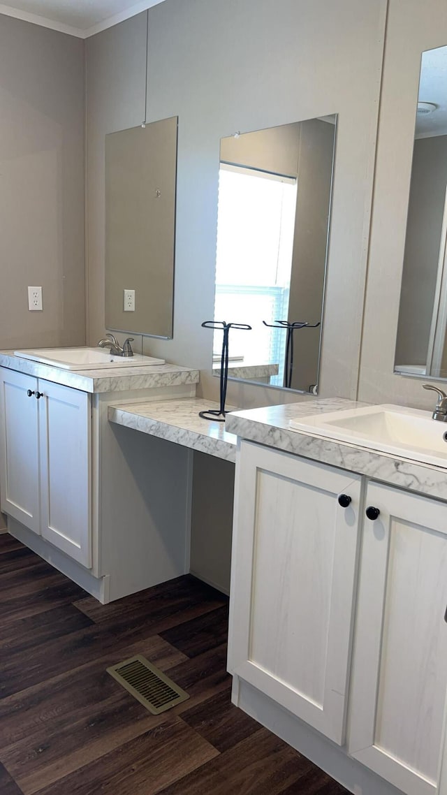 full bath featuring a sink, wood finished floors, two vanities, and visible vents