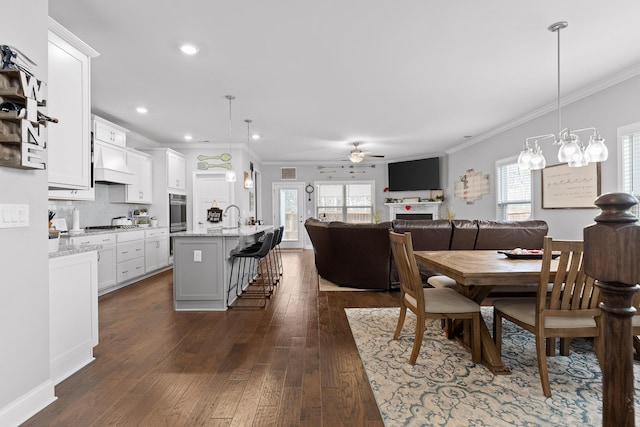 dining room with plenty of natural light, ornamental molding, ceiling fan, and dark wood-style flooring