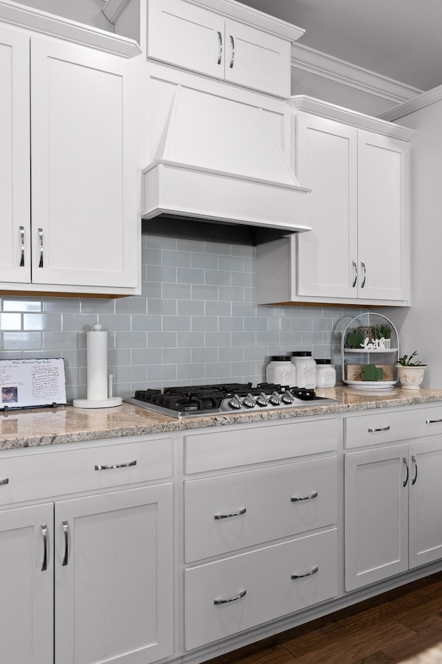 kitchen featuring premium range hood, white cabinets, ornamental molding, backsplash, and stainless steel gas stovetop