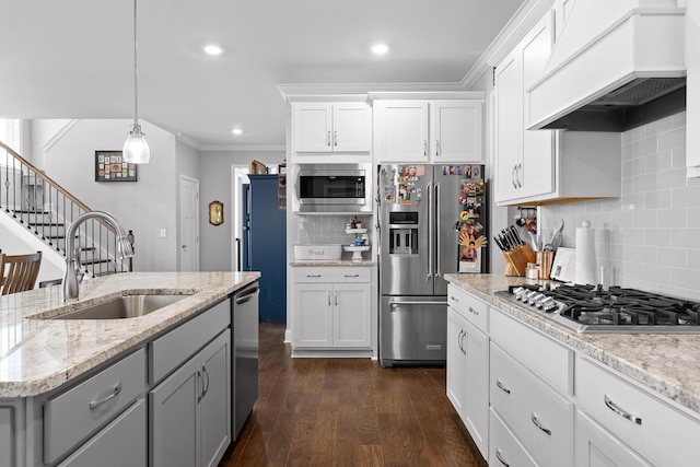 kitchen with dark wood finished floors, appliances with stainless steel finishes, premium range hood, white cabinetry, and a sink