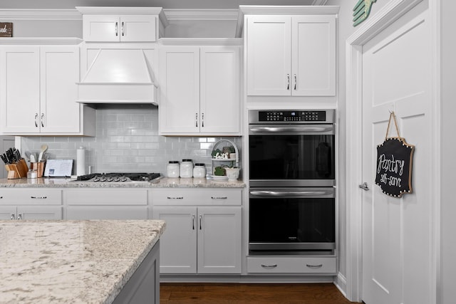 kitchen featuring stainless steel appliances, backsplash, custom exhaust hood, and white cabinets