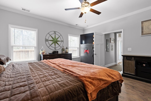 bedroom featuring ornamental molding, visible vents, baseboards, and wood finished floors