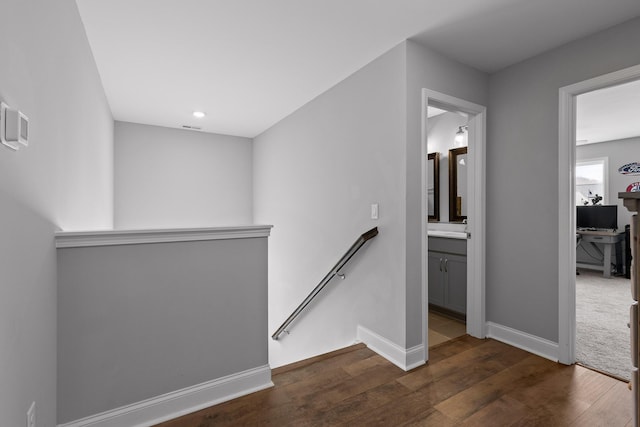 corridor with dark wood-style flooring, an upstairs landing, and baseboards