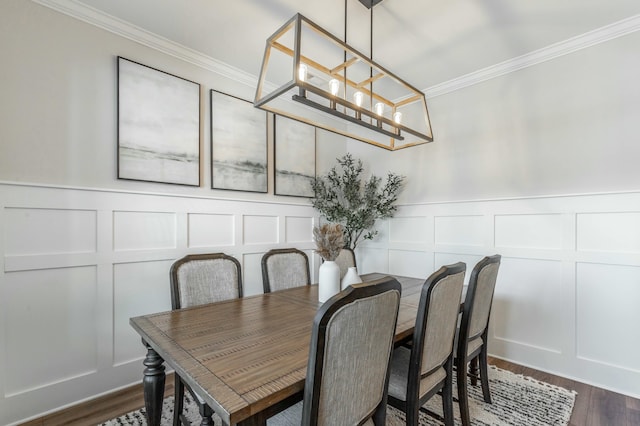 dining room featuring a notable chandelier, dark wood-style flooring, a decorative wall, and crown molding