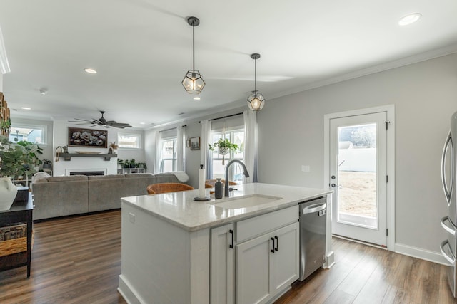 kitchen featuring appliances with stainless steel finishes, white cabinetry, a sink, an island with sink, and light stone countertops