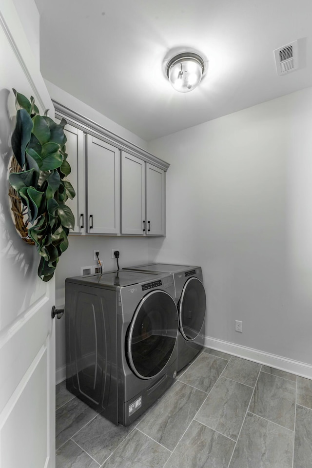 clothes washing area featuring cabinet space, baseboards, visible vents, and washer and dryer