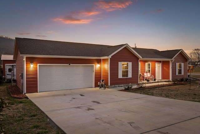 ranch-style home with a garage, driveway, a shingled roof, and a porch