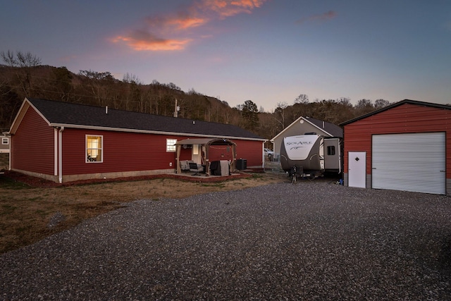 view of front of property featuring gravel driveway, a garage, and an outdoor structure