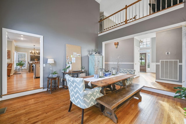 dining room with an inviting chandelier, visible vents, a high ceiling, and wood finished floors