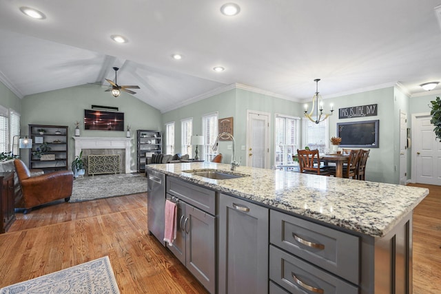 kitchen with light wood-style flooring, a sink, gray cabinetry, a fireplace, and stainless steel dishwasher