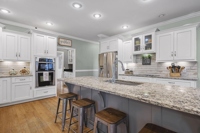 kitchen featuring white cabinetry, appliances with stainless steel finishes, a kitchen breakfast bar, and a sink