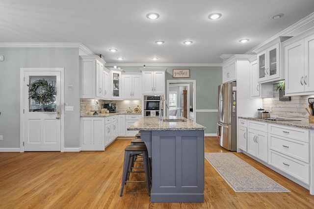 kitchen featuring appliances with stainless steel finishes, a sink, a breakfast bar, and white cabinets