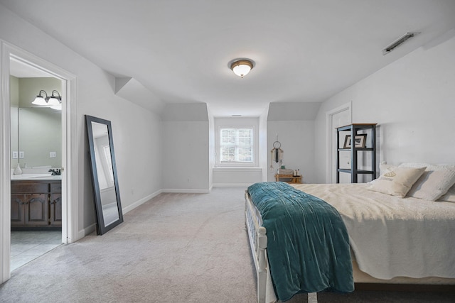 carpeted bedroom featuring connected bathroom, a sink, visible vents, and baseboards