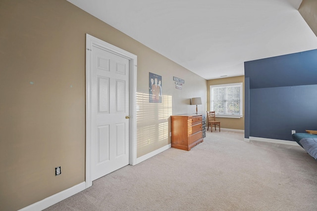 bedroom with lofted ceiling, light carpet, and baseboards