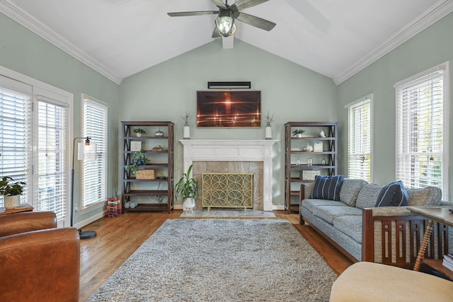 living area featuring crown molding, lofted ceiling, a high end fireplace, ceiling fan, and wood finished floors