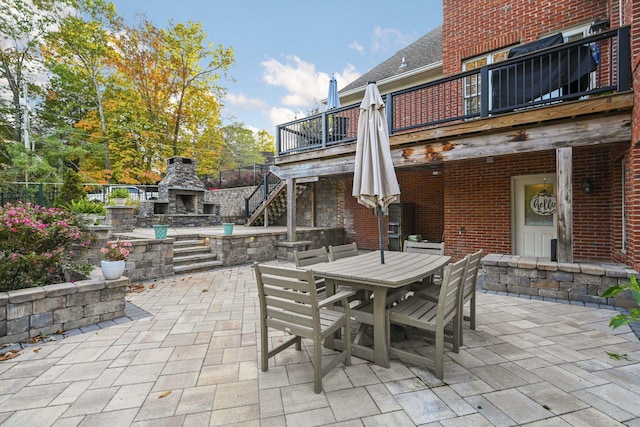 view of patio featuring stairs, outdoor dining space, and an outdoor stone fireplace