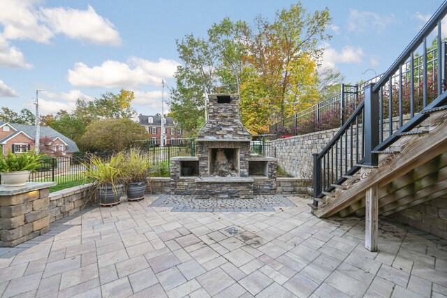 view of patio / terrace with an outdoor stone fireplace, fence, and stairway