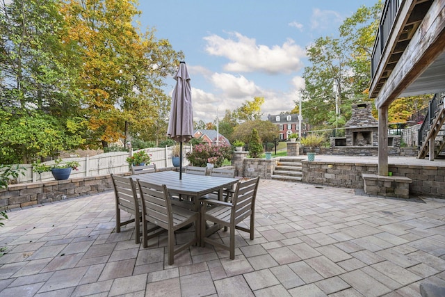 view of patio / terrace with an outdoor stone fireplace, fence, and outdoor dining area