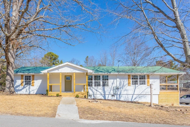 ranch-style home featuring a porch and metal roof