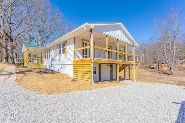 view of side of property featuring gravel driveway and a wooden deck